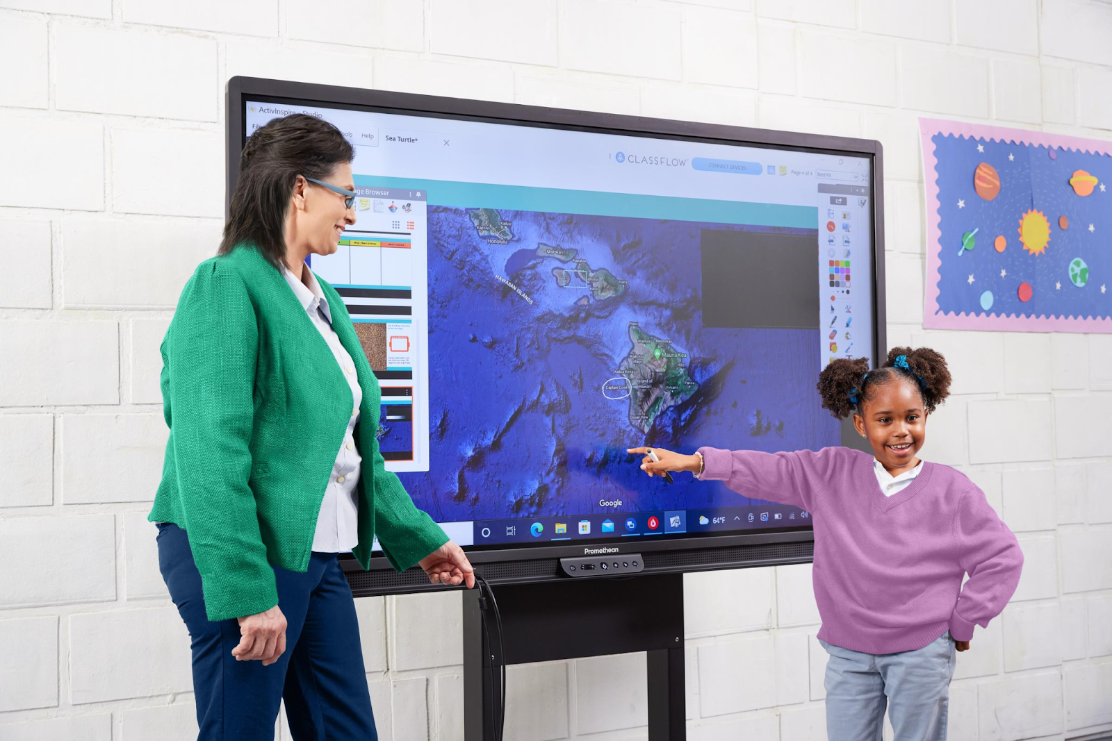 A teacher presenting to a class as a schoolchild uses an interactive display.